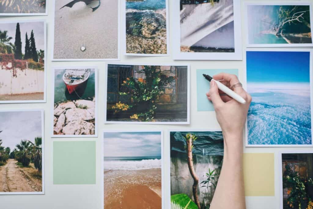 many photographs on a wall, with woman's hand writing on blank sticky note.
