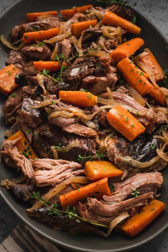 Close up of shredded porloin roast with carrots in a crockpot.