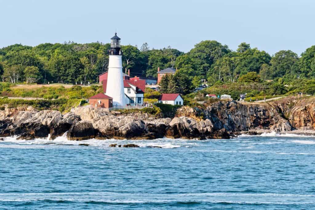 What to do in Main in May. Visiting Portland Head Light on rocky shore from the ocean.