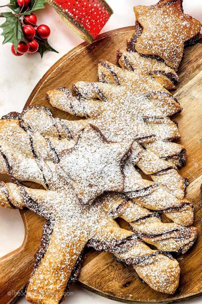 A golden Pull-Apart Nutella Christmas Tree pastry filled with chocolate hazelnut spread, shaped with twisted branches and a star on top, and generously dusted with powdered sugar.