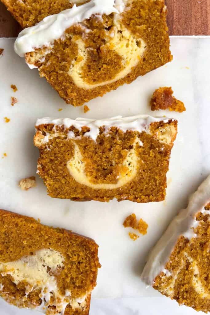 Four slices of pumpkin bread with swirled cream cheese & cream cheese icing. 