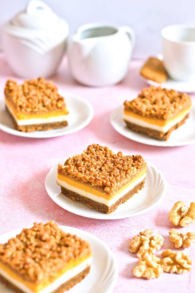 Four plates with fall dessert squares of pumpkin cheesecake bars, with one in focus. 