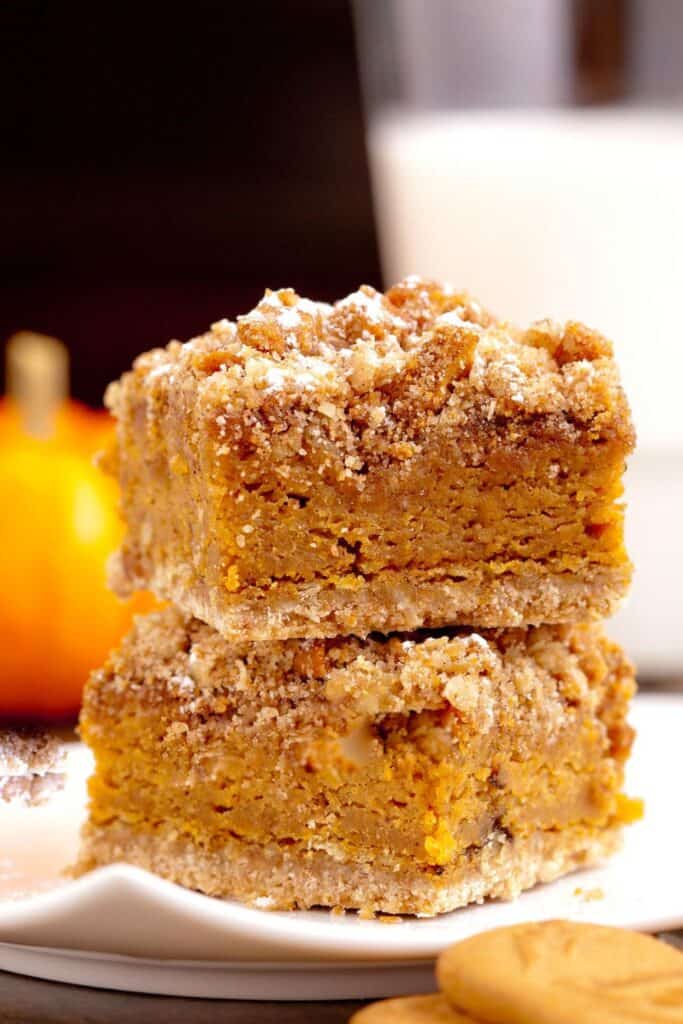 Two pumpkin pie bars with crumble topping stacked on top of each other. 