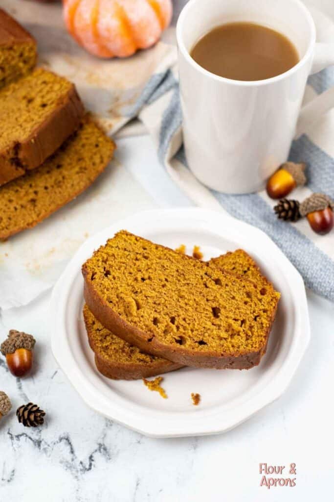 Plate with two slices of pumpkin pound cake besdie a cup of coffee. 