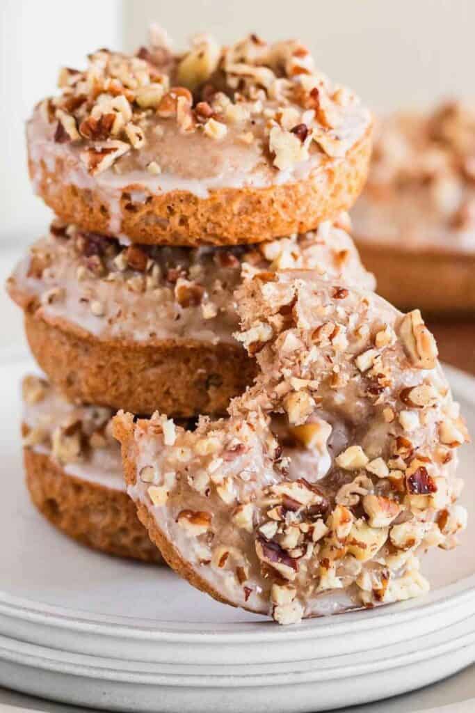 Plate stacked with 4 pumpkin spiced glazed donuts with pecans 