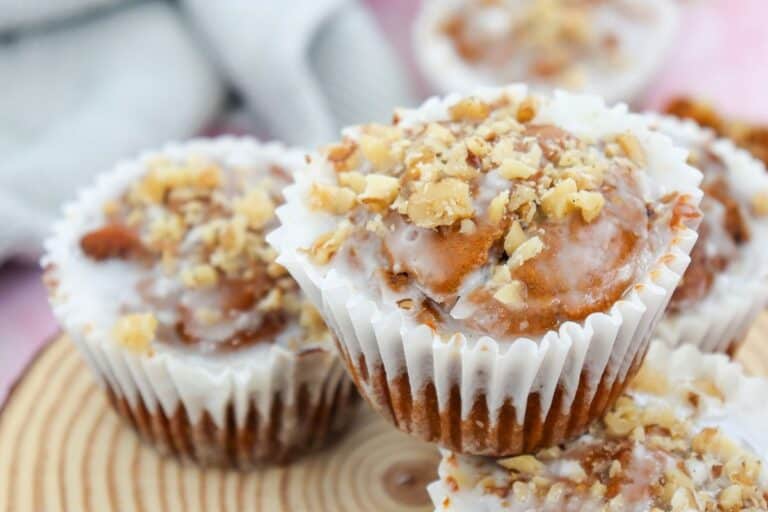 Close up of pumpkin spice muffins with icing drizzle and pecan pieces on top.