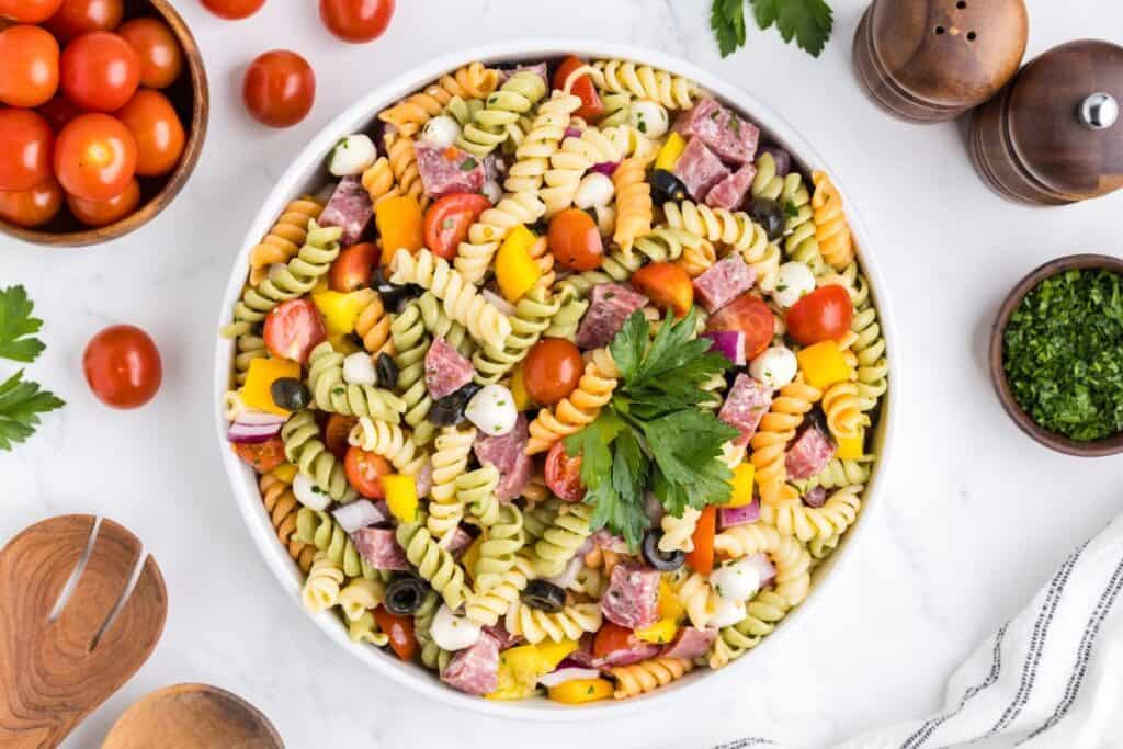 Tri colored pasta salad with Italian dressing, cherry tomatoes, mozarella balls, parsley, yellow peppers, salami.