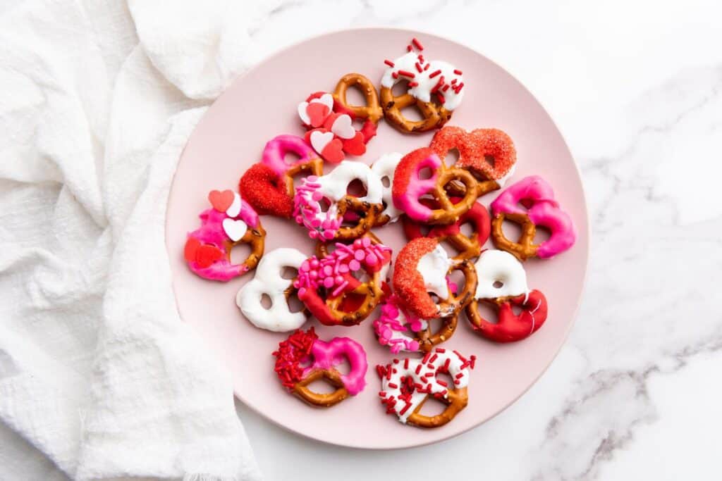 A plate of Valentine's pretzels, decorated with red, white and pink candy melts and sprinkles.