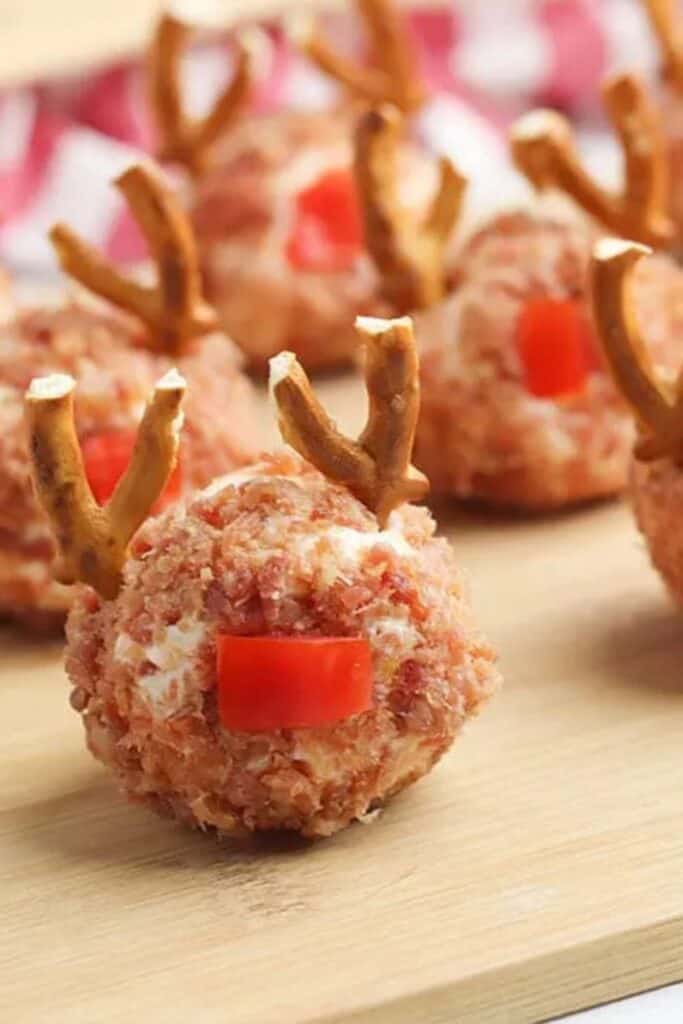 Close up of a Reindeer min icheeseball with pretzel antlers, and red pepper nose.