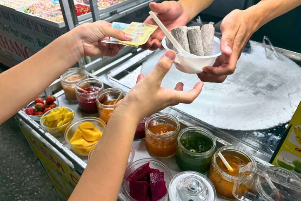 Hands exchanging money and rolled ice cream at Phu Quoc's Night Market.