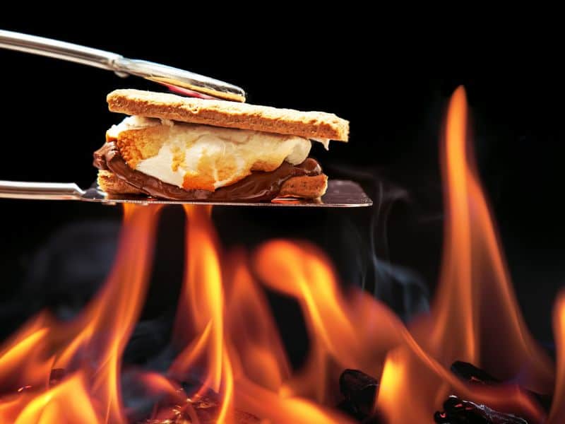 Cooking S'mores over a campfire with metal tongs