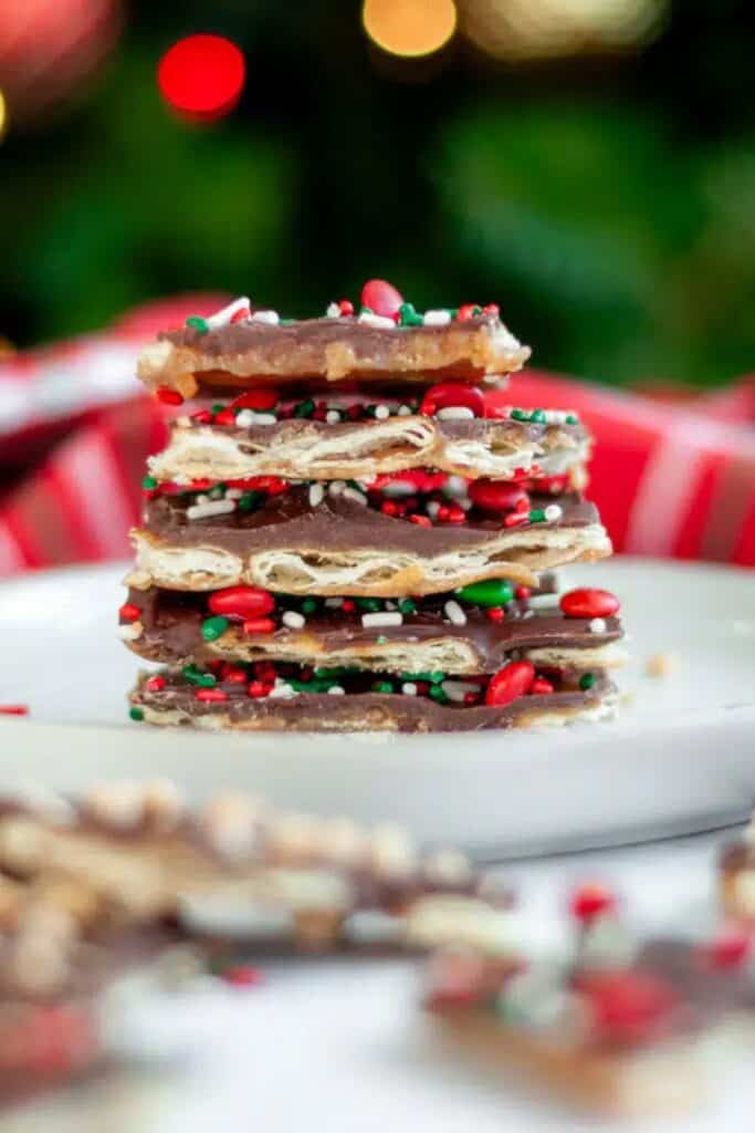 Stack of Saltine Cracker Toffee topped with a rich chocolate layer and festive red, green, and white sprinkles.