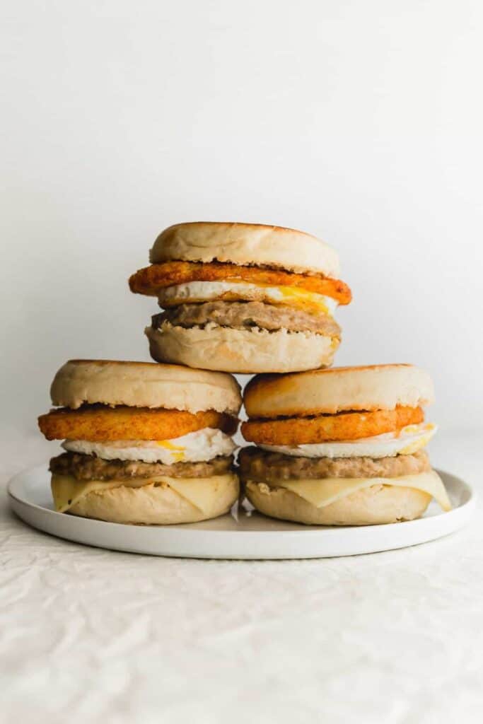 Stack of three breakfast sandwiches with egg, sausage & hashbrown 