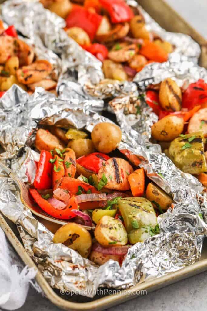 Four campfire tinfoil packs filled with sausage, potatoe and peppers. 