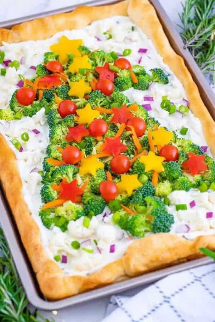 Savory Rectangle pizza crust, layered with cream cheese mix and topped with broccoli, and cherry tomatoes in the shape of a Christmas tree.  