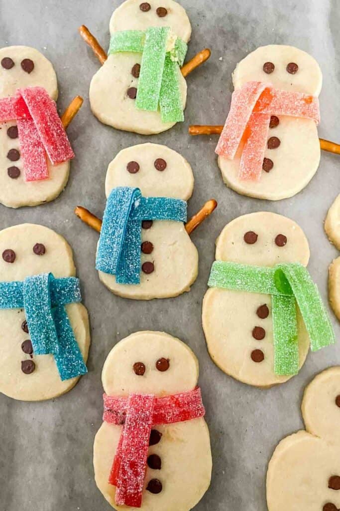 Cute Christmas shortbread snowmen with candy scarves, chocolatechip eyes. 