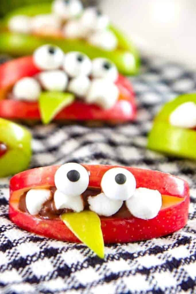 Apple slice monsters with chocolate and mini marshmallows for teeth, and candy eyes. 