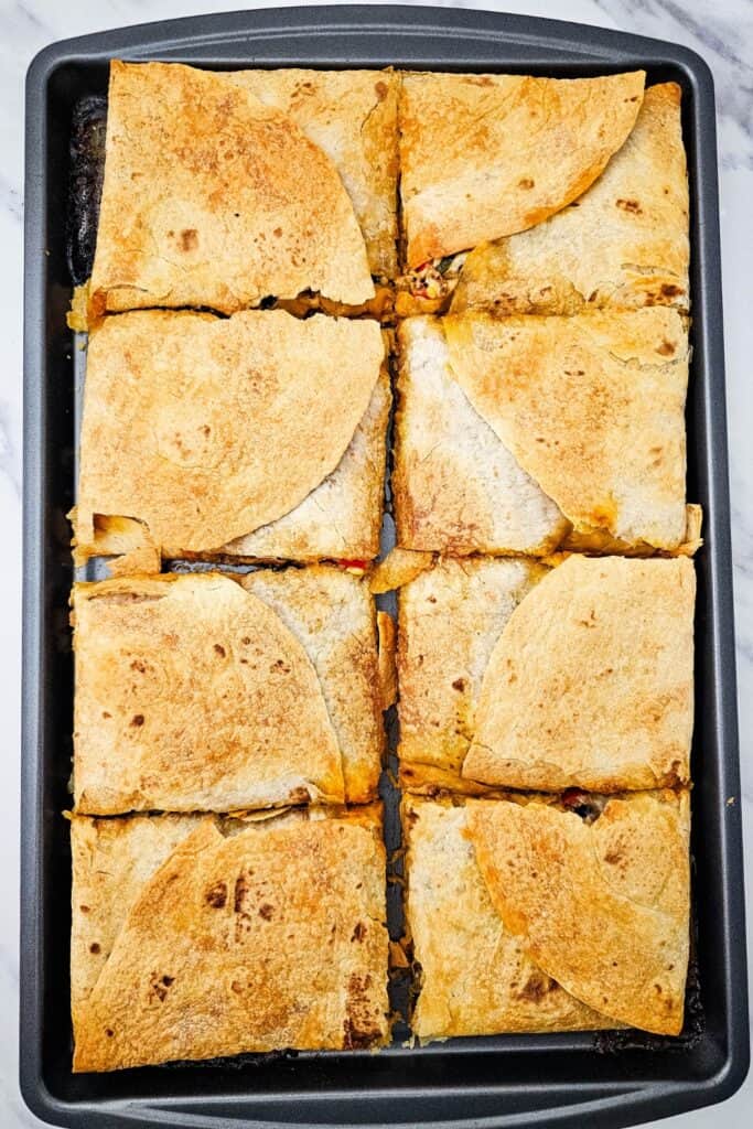 Baked sheet pan quesadillas cut into neat squares, showcasing a golden, crispy tortilla crust ready to serve. Perfect for easy weeknight dinners, this one-pan meal offers a cheesy, hearty filling packed with Tex-Mex flavor.