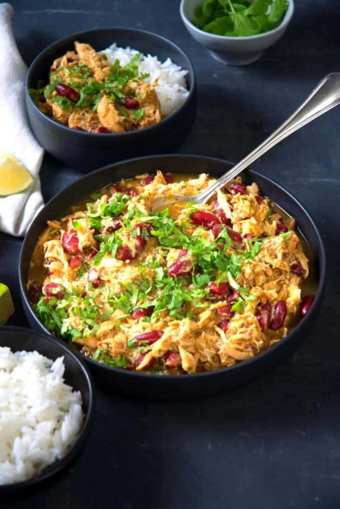 Bowl of Mexican Shredded Chicken with red beans and parsley for garnish.