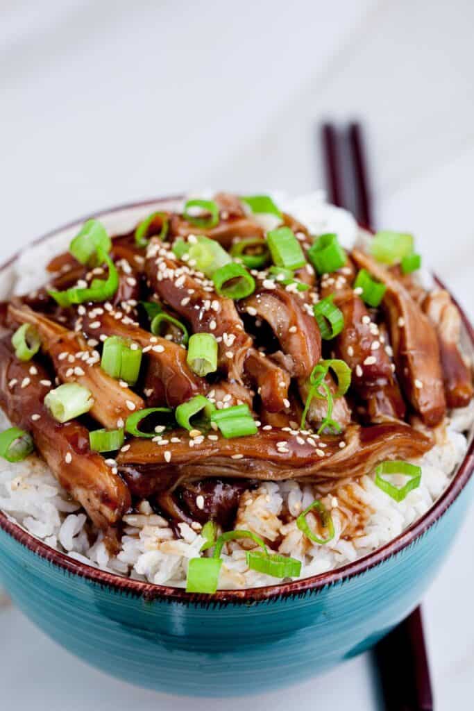 Pottery bowl filled will chicken teriyaki and rice. 