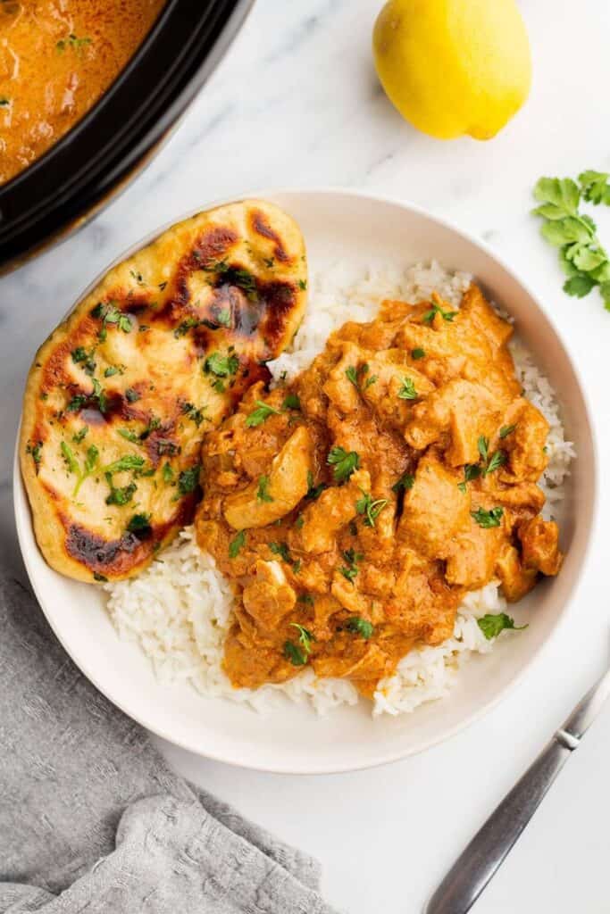 Plate of Chicken Tikka Masala over basmati recipe and a piece pf Naan bread. 