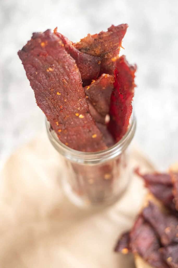 Small mason jar filled with strips of smoked beef jerky. 