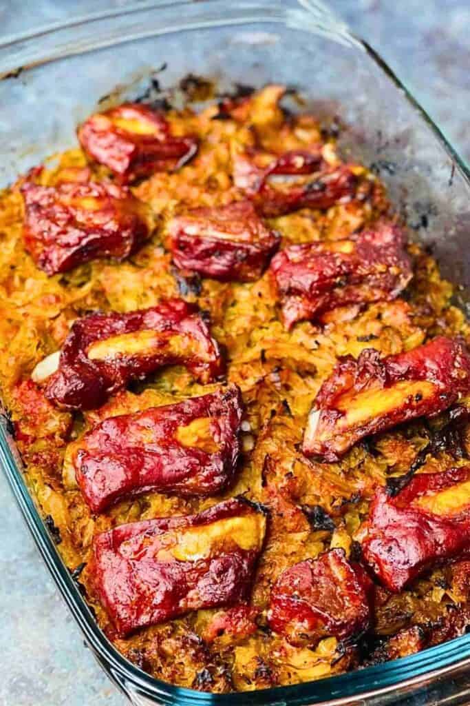 A glass baking dish filled with Smoked Pork Ribs and Cabbage Casserole, topped with caramelized, smoky pork ribs over tender seasoned cabbage baked until golden brown around the edges.