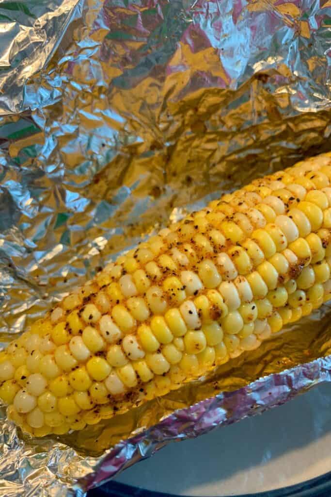 One corn on the cob covered in spices on tin foil. 