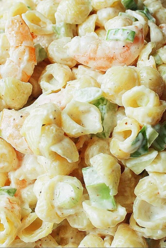 Close up of creamy spicy shrimp macaroni salad with chopped celery and green onions. 