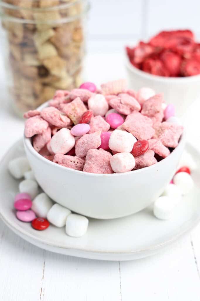 Bowl of Strawberry white chocolate covered Chex snack mix with mini marshmallows and M&Ms. 