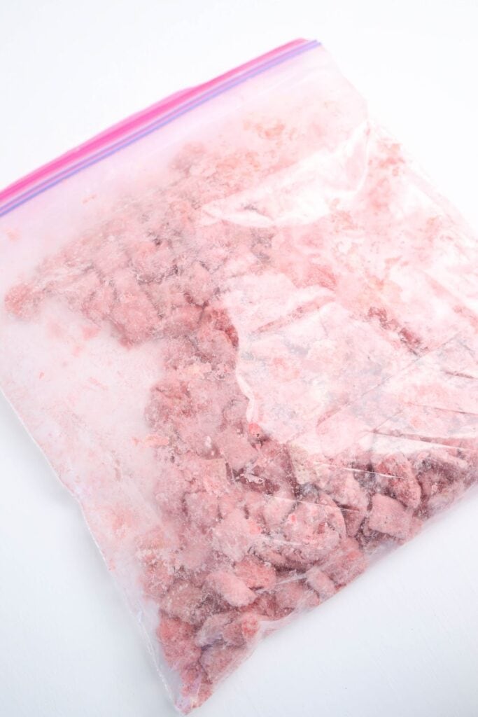 Closed Ziploc bag with chex cereal mixed with powdered strawberry sugar mix and white chocolate. 