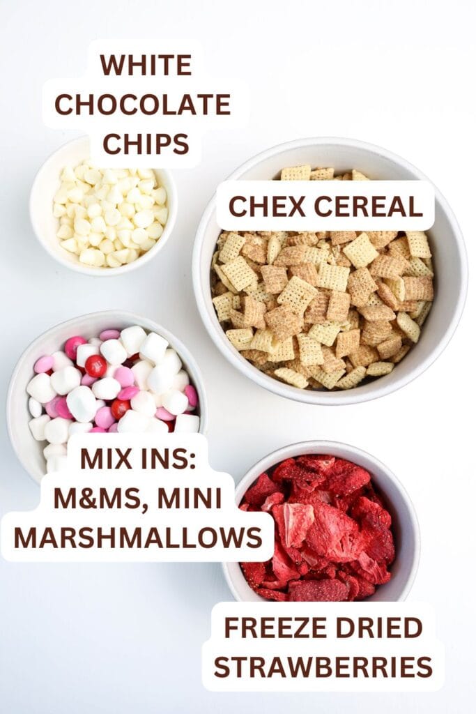 Ingredients for the Strawberry Muddy Buddies snack mix in small bowls; cinnamon Chex, white chocolate chips, freeze dired strawberries and mix ins.