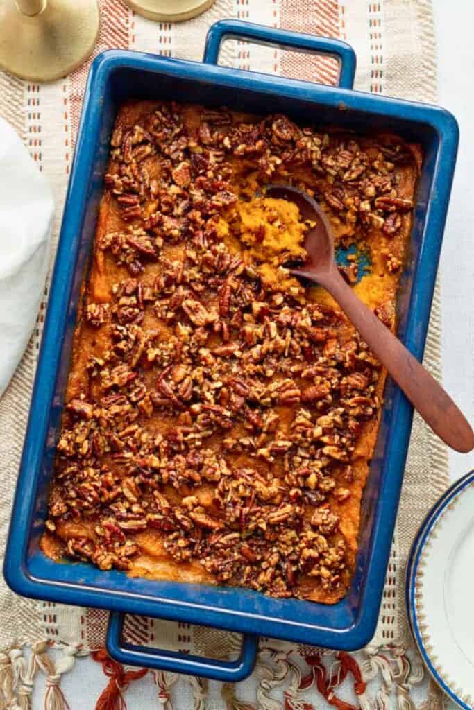 Sweet potato casserole with a smooth orange sweet potato filling topped with a crunchy brown sugar pecan streusel in a blue baking dish.