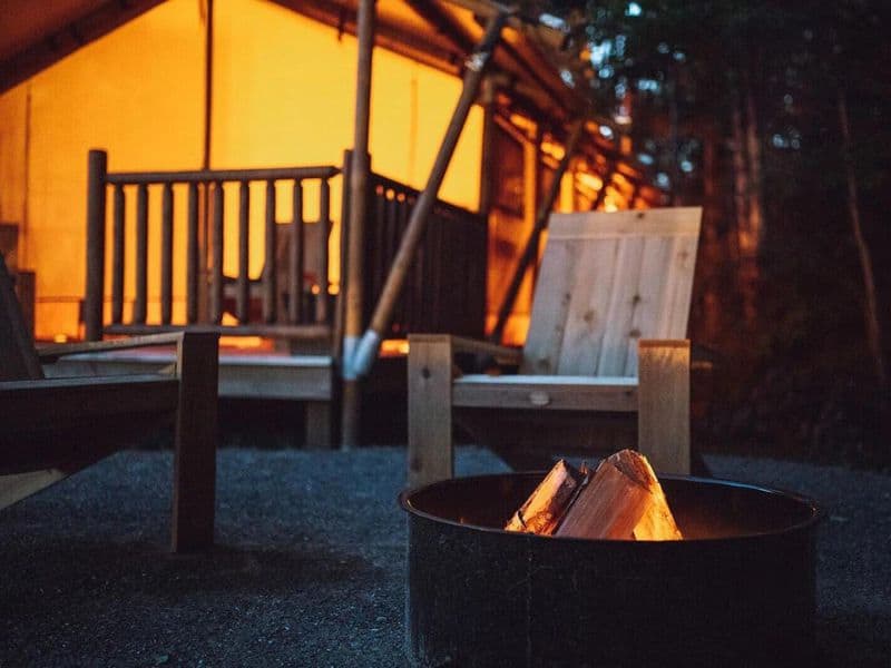 Glamping tent lit at night and campfire. 