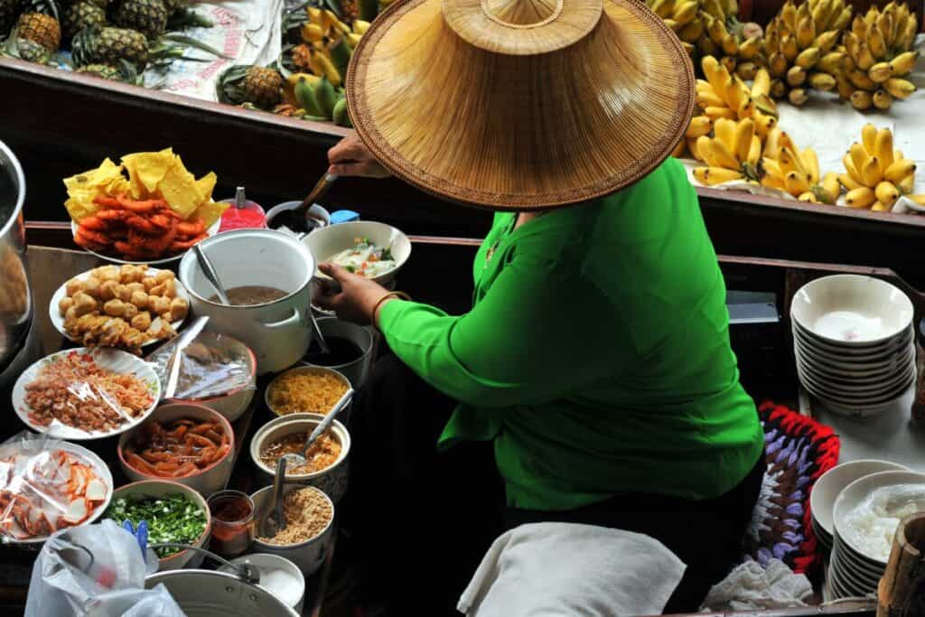 Woman serving food from a boat on a floating market in Thailand