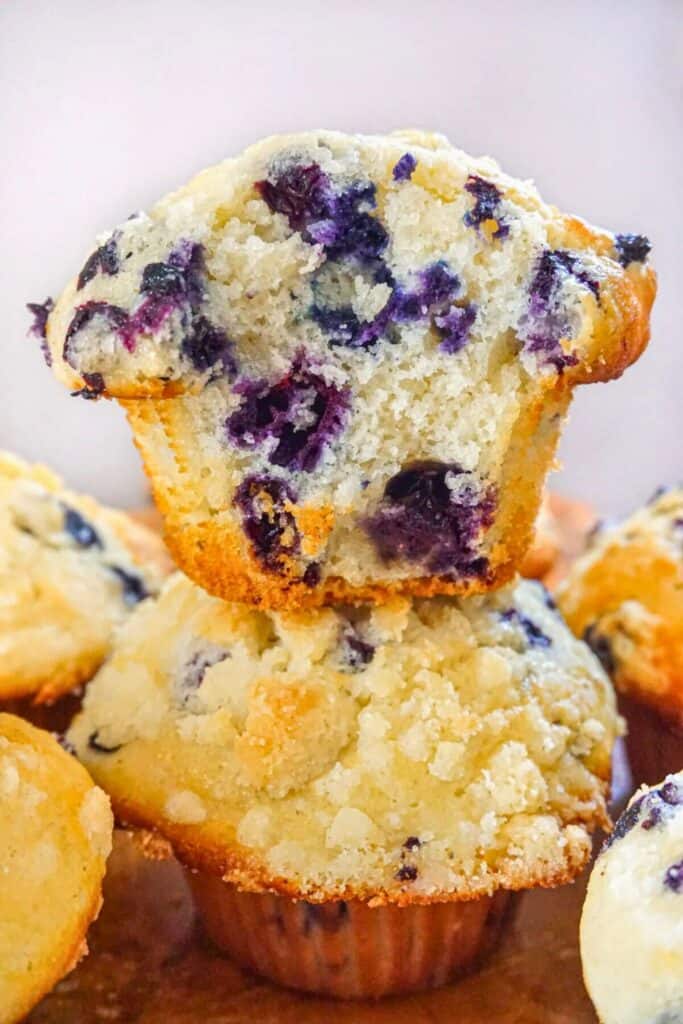 Close up of a Tim Hortons copycat blueberry muffin split in half to reveal a soft fluffy interior packed with juicy blueberries. The golden brown muffin has a lightly crisp top with a delicate crumb texture, showcasing the bakery style look and moist crumb.