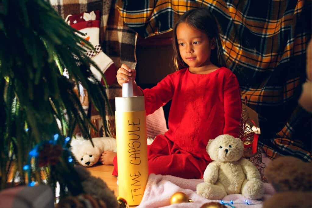 Young girl putting rolled up paper in a time capsule. 