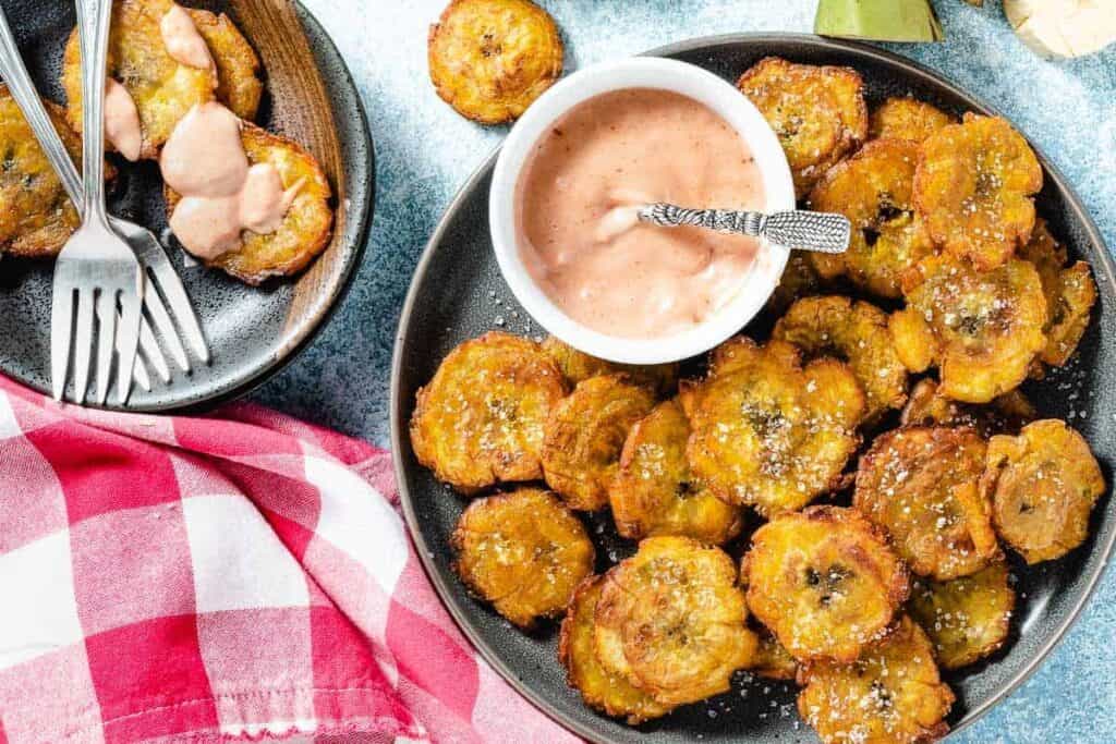 Plate of tostones around a small bowl of pink sauce.