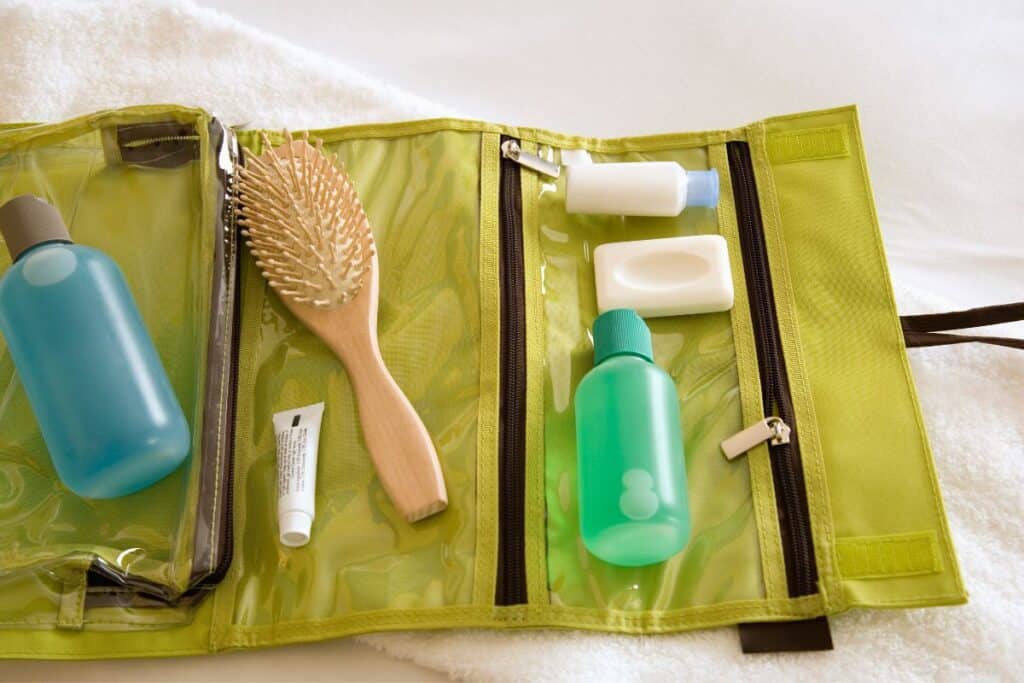 Toiletry bag open with hairbrush, soap cream, conditioner.
