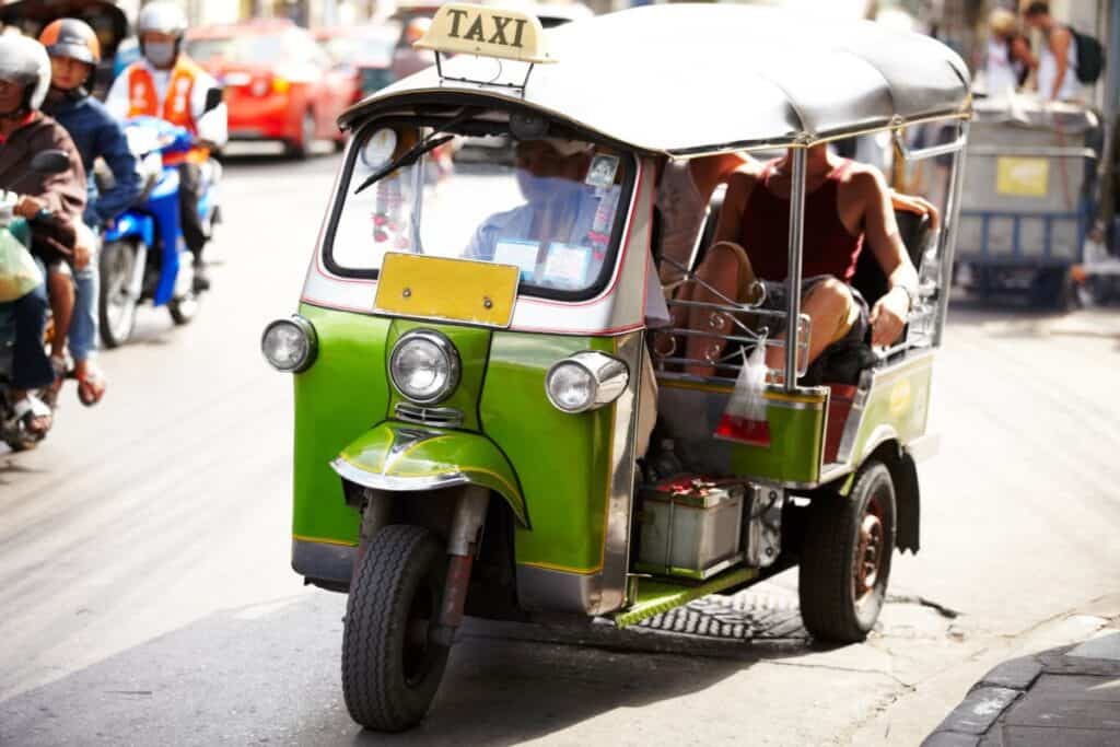 Tourists in a Tuk Tuk in Thailand on a busy street. 