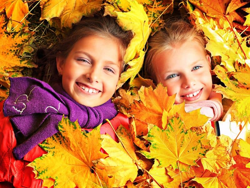 Two Girls Lying in Fall Maple Leaves