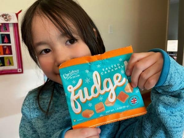 Young Girl holding a package of English Salted Caramel Fudge from Universal Yums snack box.