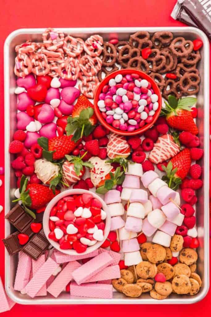 Valentine's charcuterie board with chocolate covered strawberries, cookies, candy pretzels, red fruits.