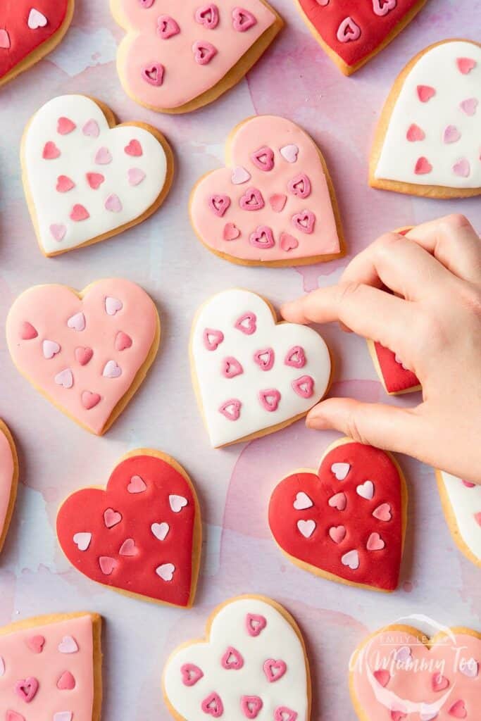 Tray of heart shpaed cookies docrated with fondant and heart shaped sprinkles. 