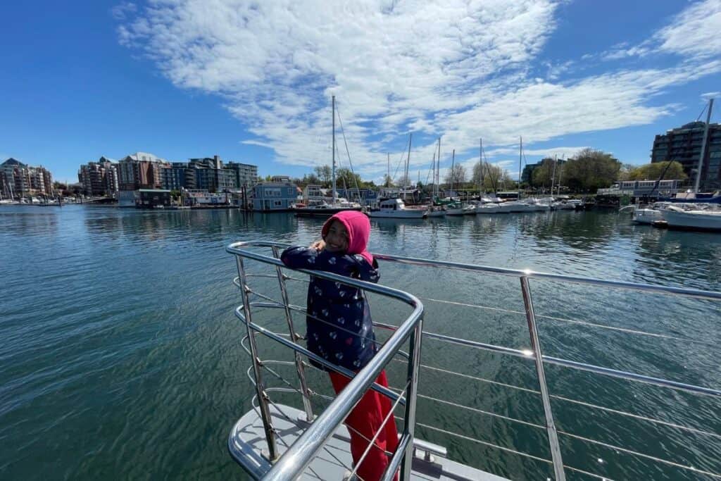 Young girl smiling at the tip of a boat heading into Victoria's harbour.