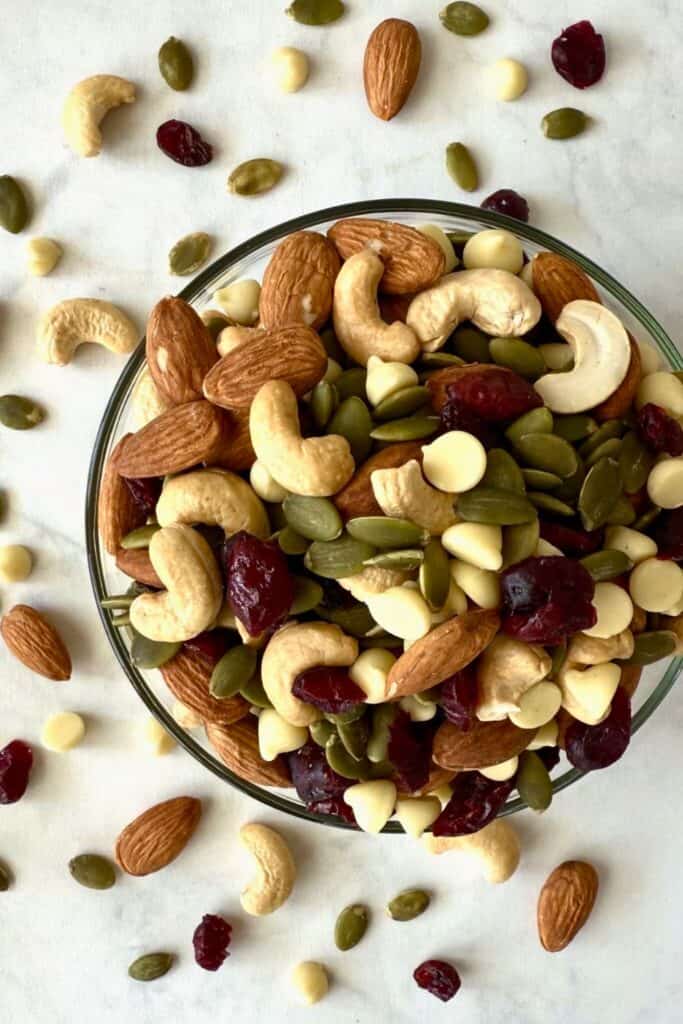 Bowl of white chocolate and cranberry trail mix filled with almonds, cashews, pumpkin seeds, dried cranberries, and white chocolate chips. The overhead view highlights the colorful mix of sweet and crunchy ingredients.