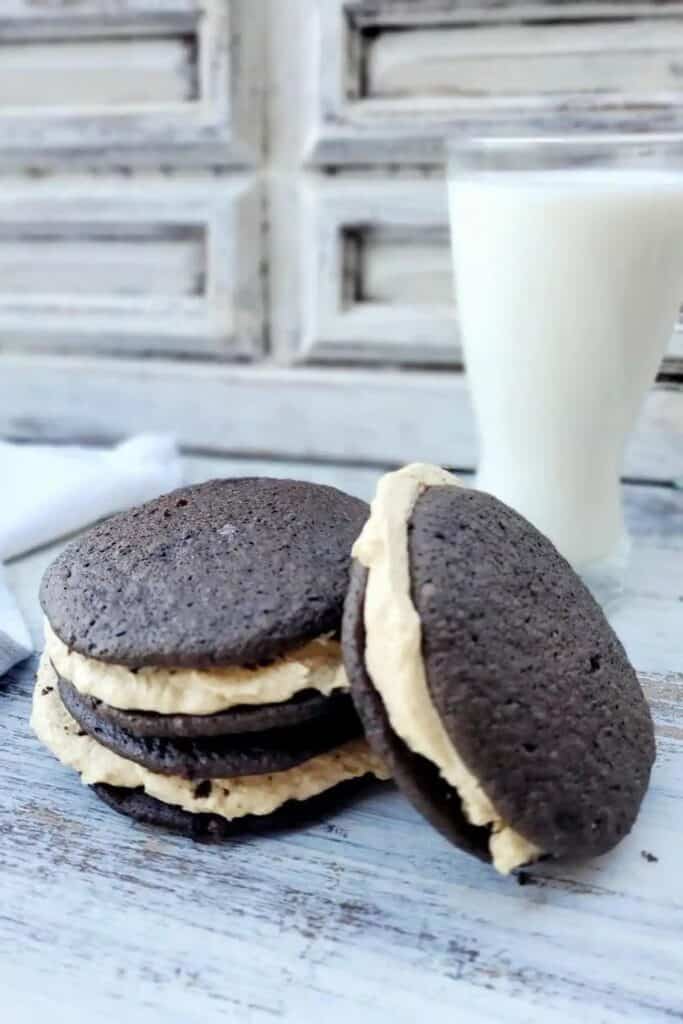 Three whoopie pies in front of a glass of milk. 