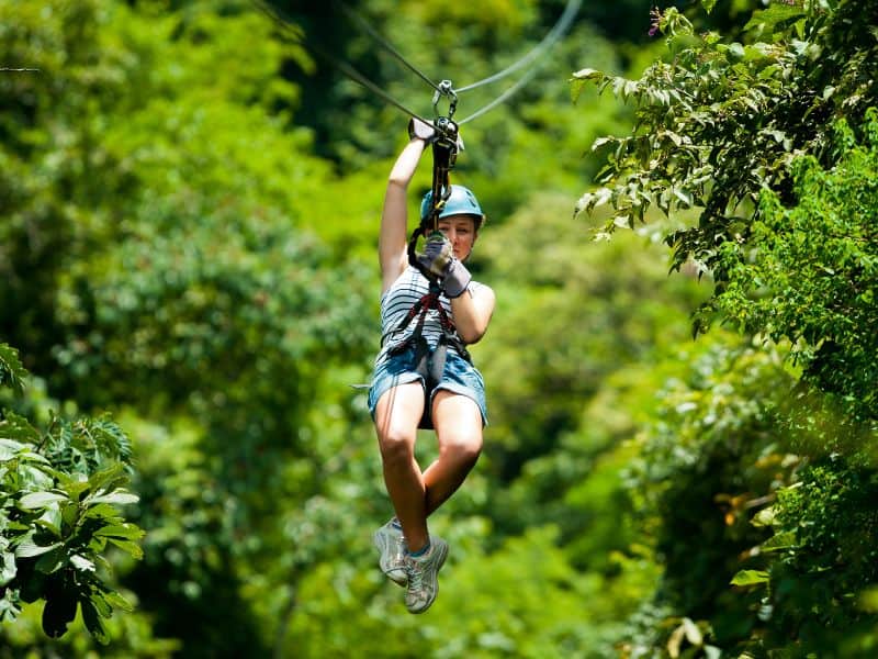woman ziplining over jungle
