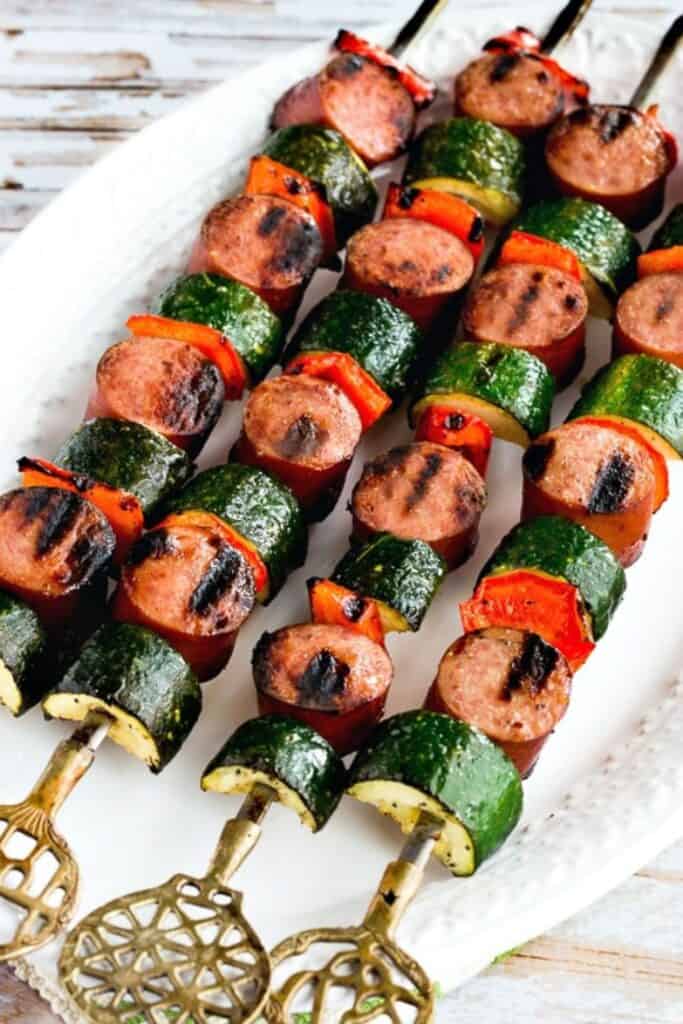 Decorative metal skewers with grilled sausage, zucchini and red pepper. 